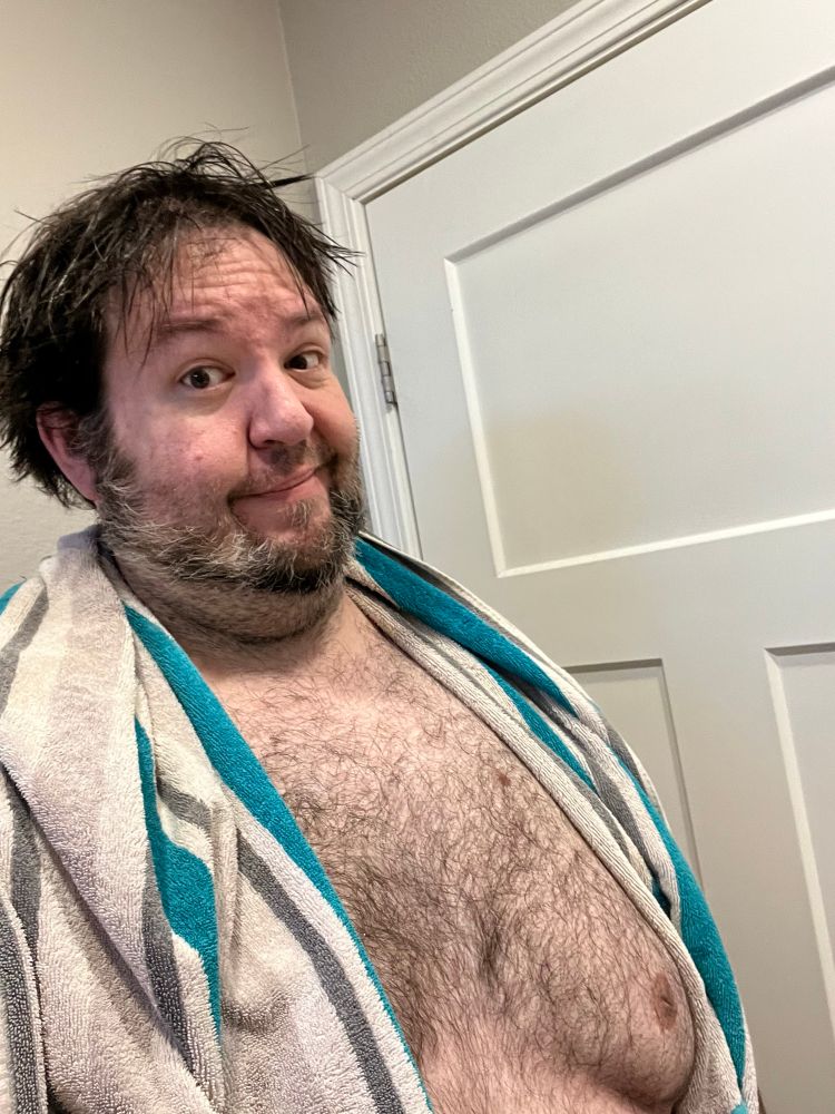 Hairy guy fresh out of the shower with a towel around his shoulders 