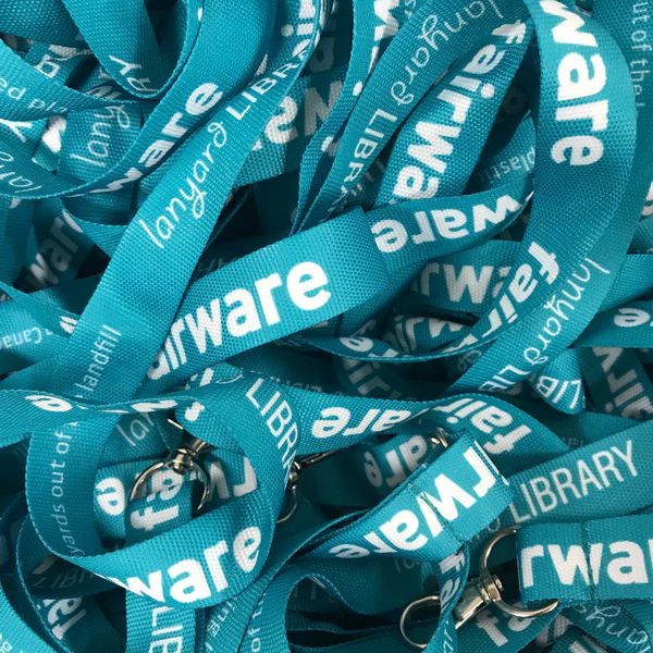 several lanyards from the Fairware lending library curled together on a teal background with white lettering.