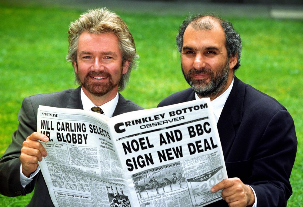 It's May 1993. Noel Edmonds and then-BBC1 controller Alan Yentob blur fantasy and reality by holding up an edition of the fictional Crinkley Bottom Observer which announces the real news that Noel and the BBC have signed a new deal.