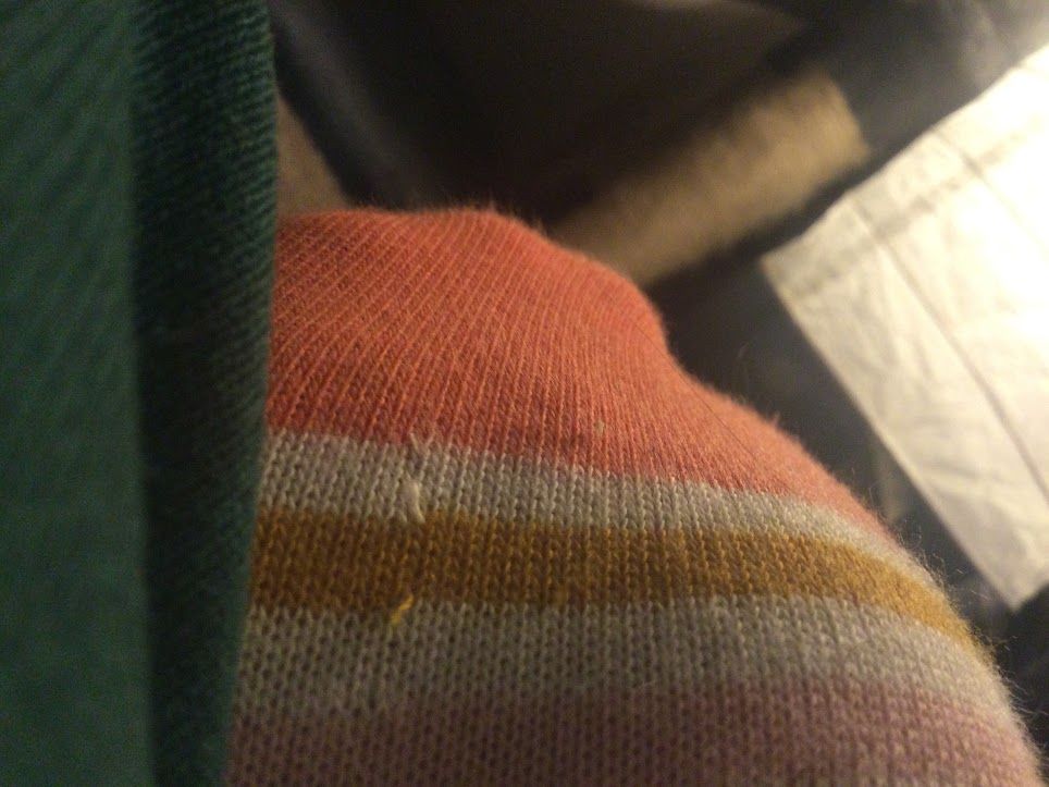 An arched foot, the ball of the foot stretched towards the camera, wearing a tight, practically sheer woman's sock, with colorful stripes. Pink, beige, mustard yellow, cream, salmon and a bright orange are the sock's colors. The viewer has been shrunk to microscopic size. Unfortunately, the photographer shrunk a lot more than their camera did, and is currently lost.