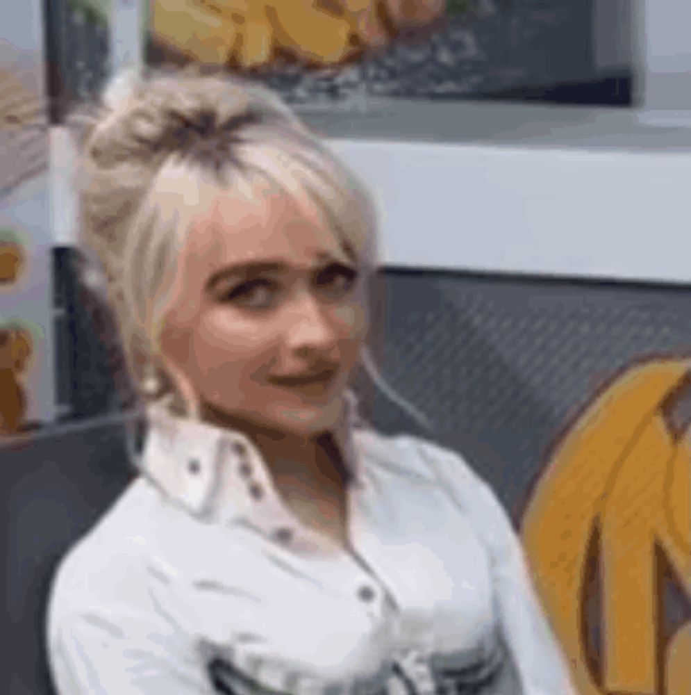 a woman in a white shirt is sitting in front of a window in a restaurant .