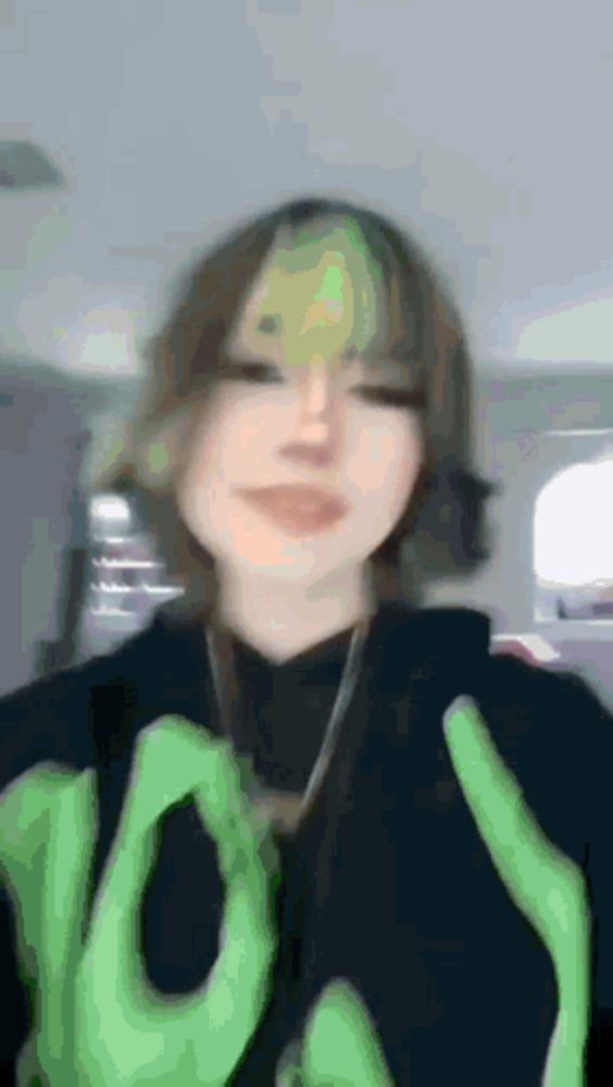 a blurry picture of a girl wearing a black hoodie with green hands on it .