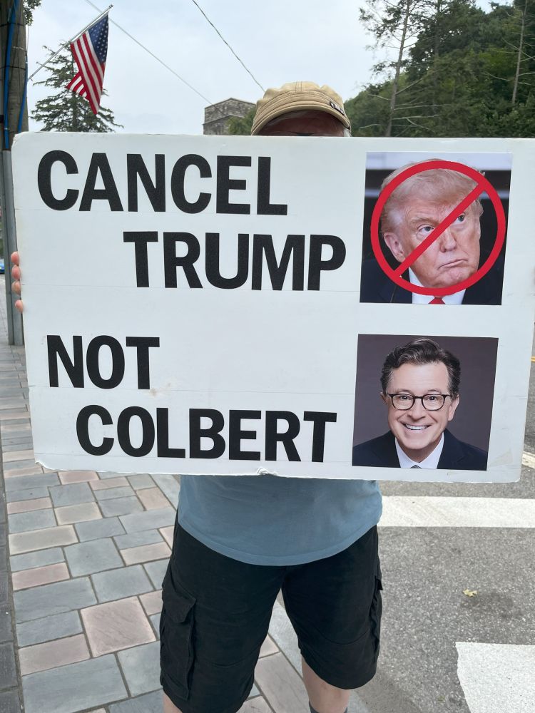 Husband's sign reads above "Cancel (47)" with a photo of his face circled and crossed out in red and below "Not Colbert" with a photo of Steven.