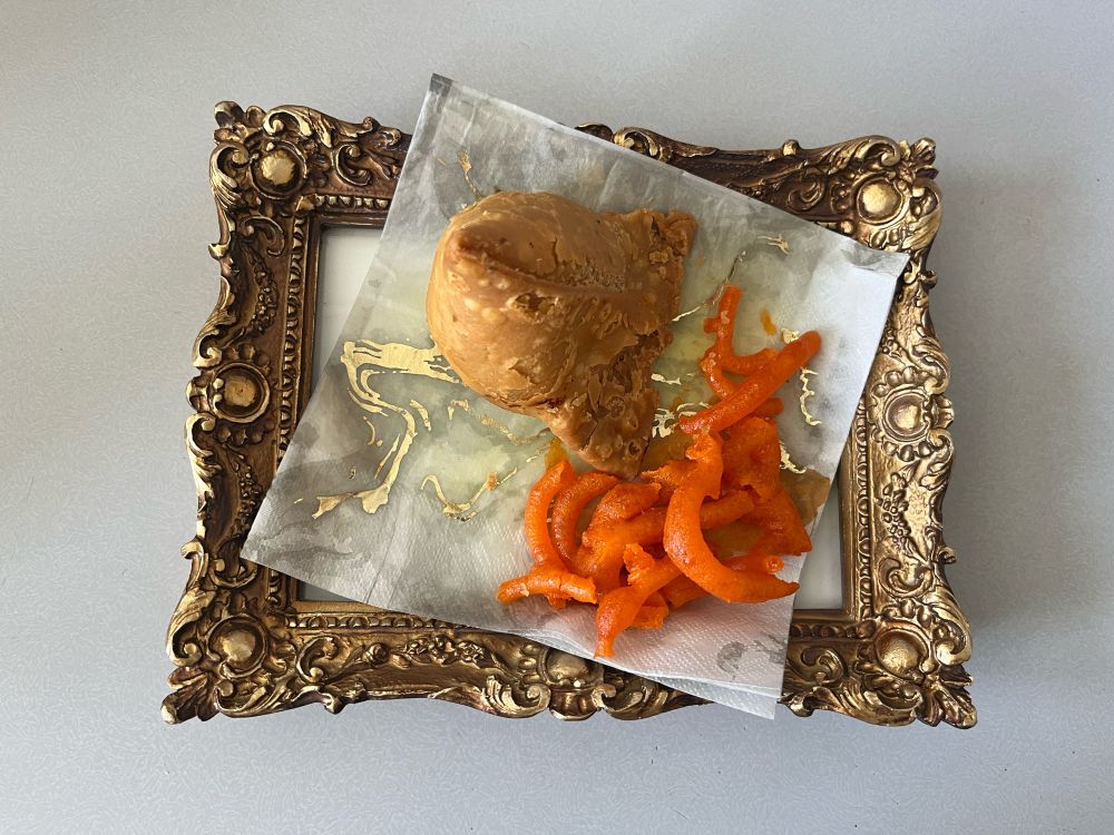 a samosa and jalebi sitting on a photoframe because I didn’t have any plates