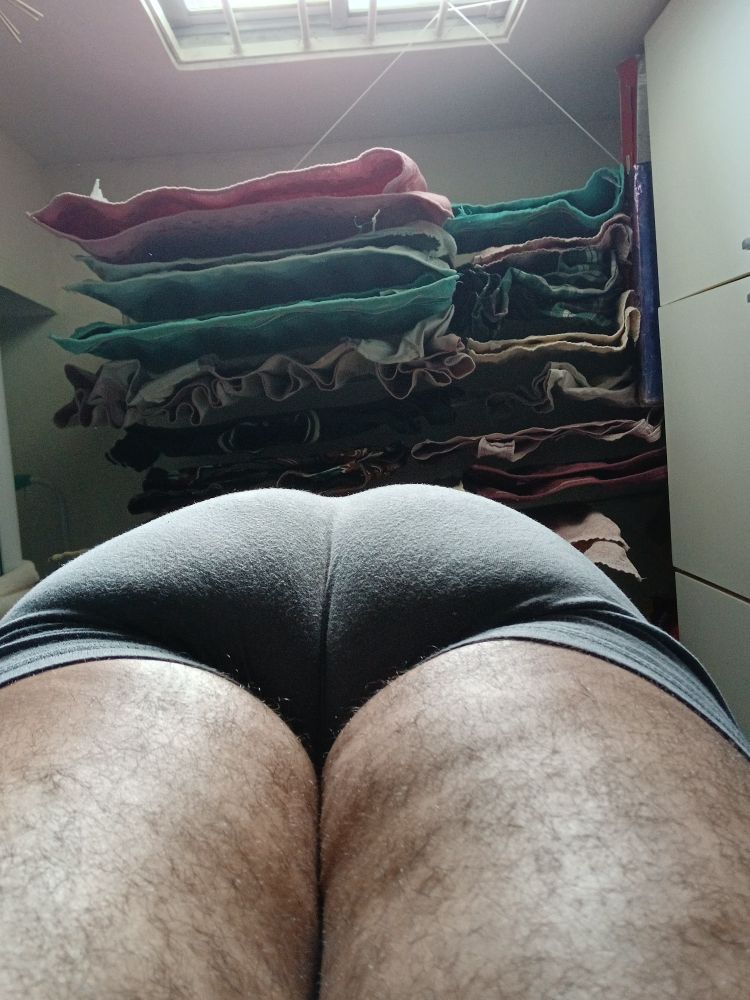 Foto tirada de baixo, mostrando minha bunda e parte das minhas pernas. Estou usando uma cueca cinza.