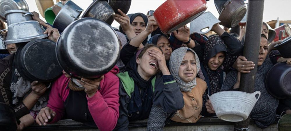 Des personnes, surtout de jeunes femmes et filles, attendent de la nourriture avec des casseroles, pressées dans une foule compacte. Certaines pleurent. Toutes ont l'air désespéré. Photo World Health Organization