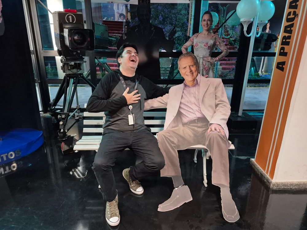 Eu sentado no banco da Praça rindo muito ao lado do Carlos Alberto de Nobrega de papelão 