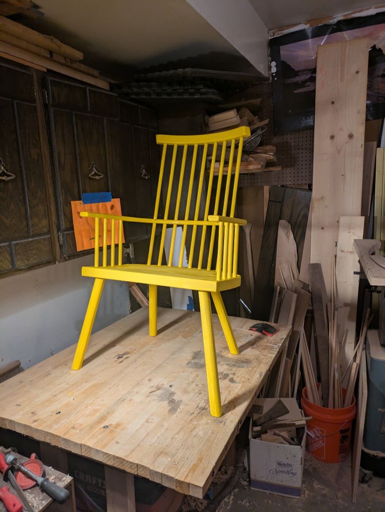 A chair is set on a work bench, painted a bright yellow