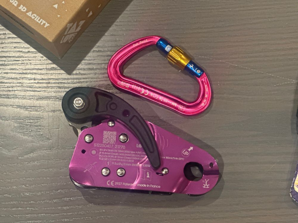 A purple taz love 3 ascender and a pink CAMP carabiner sitting on a table
