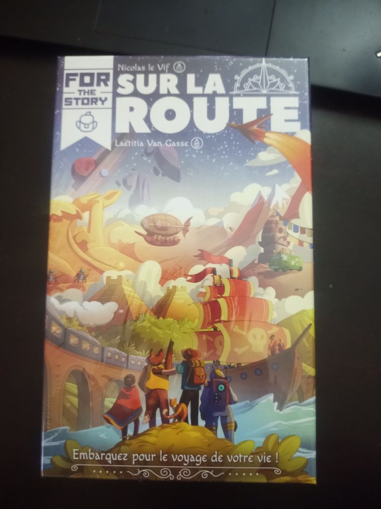 Jeu de société / jdr narratif qui représente un groupe de personnes de tous horizons regardant un monde pleins de bateaux, de pyramides, d'avions et de montgolfière, et de paysages splendides. Le type blanc et en lettre capitales avec une moitié de boussole sur le dessus : For The Story - Pour la Route. 