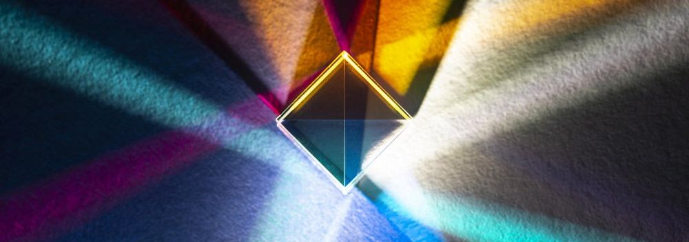 Im Bild ist ein Diamant im Vordergrund zu sehen, der von Farben wie Blau, Rot, Gelb und Grün umgeben ist. Diese Farben schaffen eine dynamische und ansprechende Atmosphäre.
