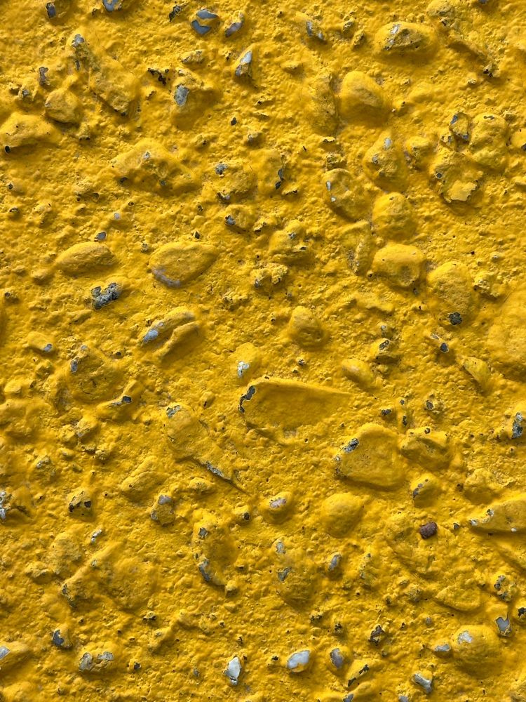 Bumpy cement full of rocks, painted yellow