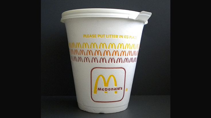 White styrofoam McDonald's cup; the McDonald's is large at the bottom and above that there are three rows of just the M symbol much smaller; the top row is yellow, the next is orange, and the last is reddish-brown. Above all of that is the text, "Please put litter in its place." There's a white plastic lid on the cup.
