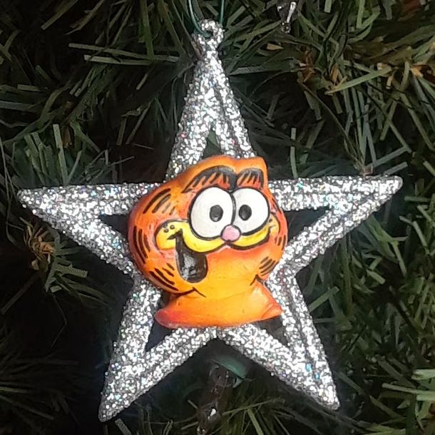 A Christmas ornament that's a glitter-covered star with Garfield's face in the middle