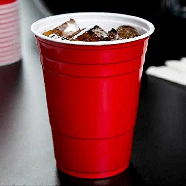 The solo cup; a red plastic with a white rim and white interior. There are ice cube and what looks like cola or root beer inside.