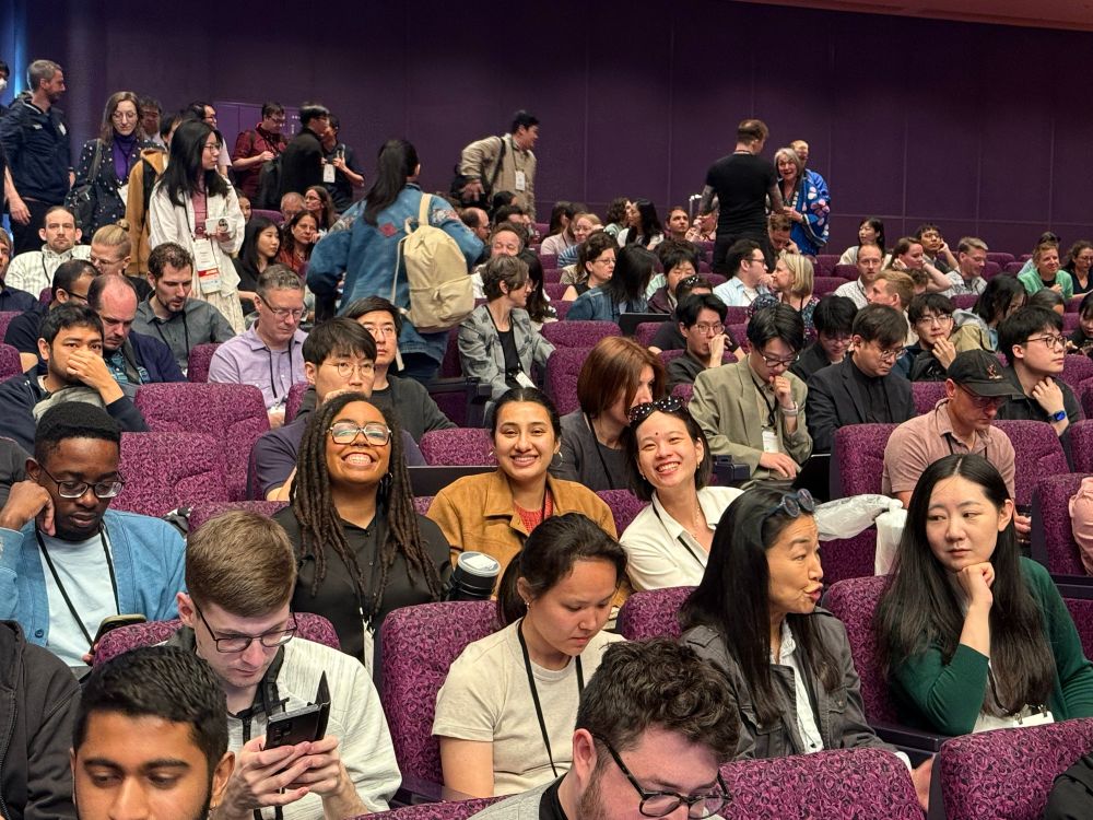 Tilar and Ritika smiling in their seats as they wait for the start of the opening plenary. 