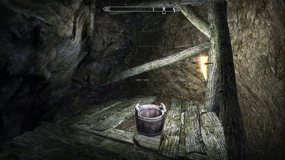 Un seau servant de toilette dans une grotte sur Skyrim.