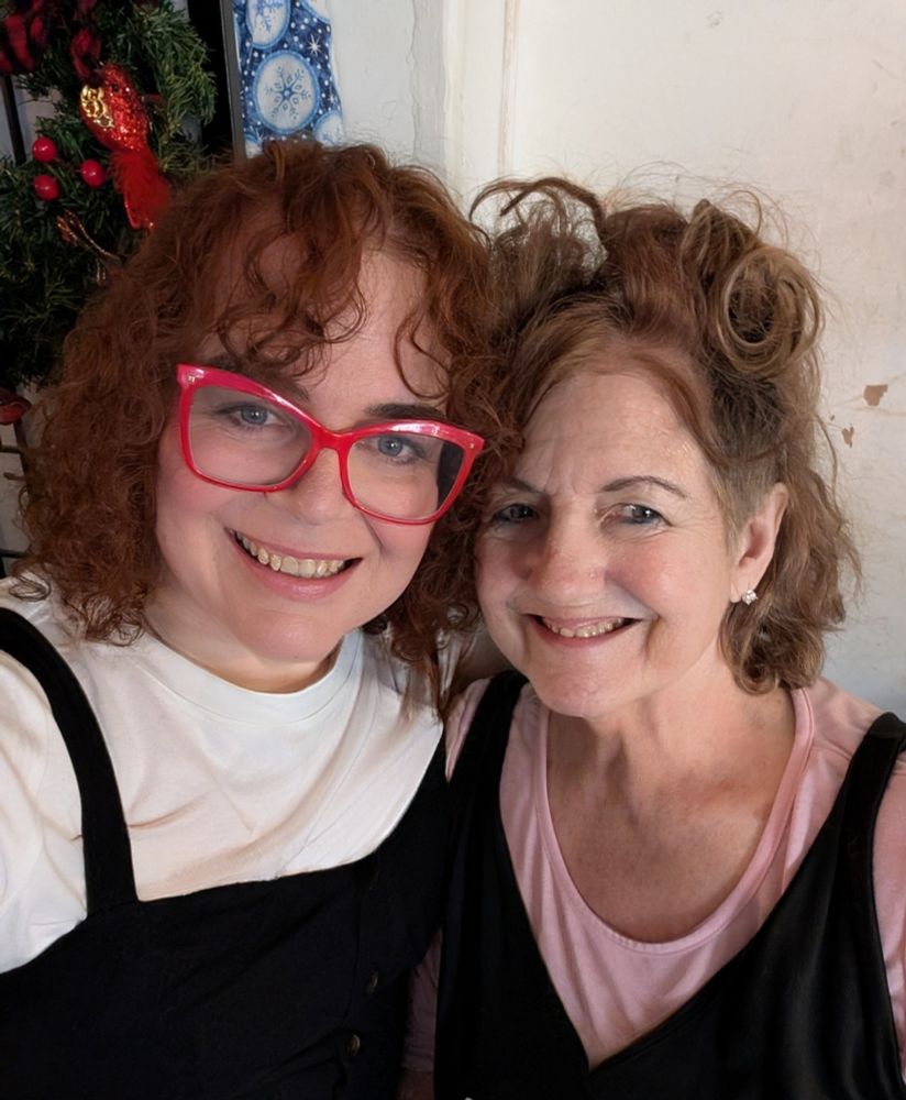 Two curly haired women, a daughter and mother smiling at the camera