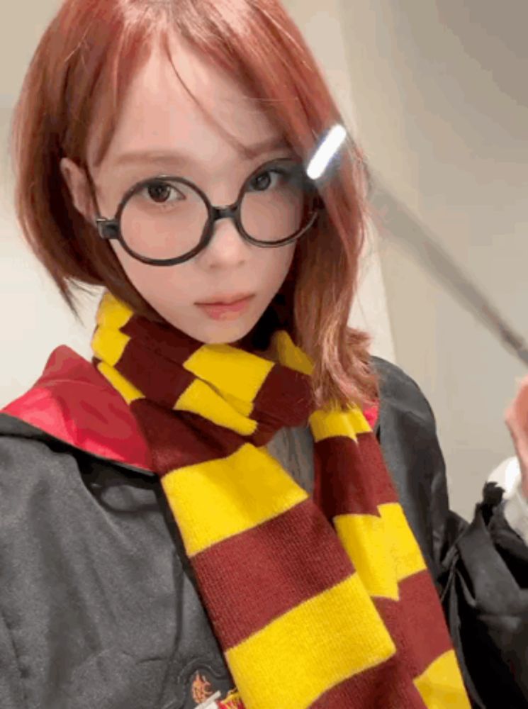 a girl with red hair wearing glasses and a scarf with the letter h on it