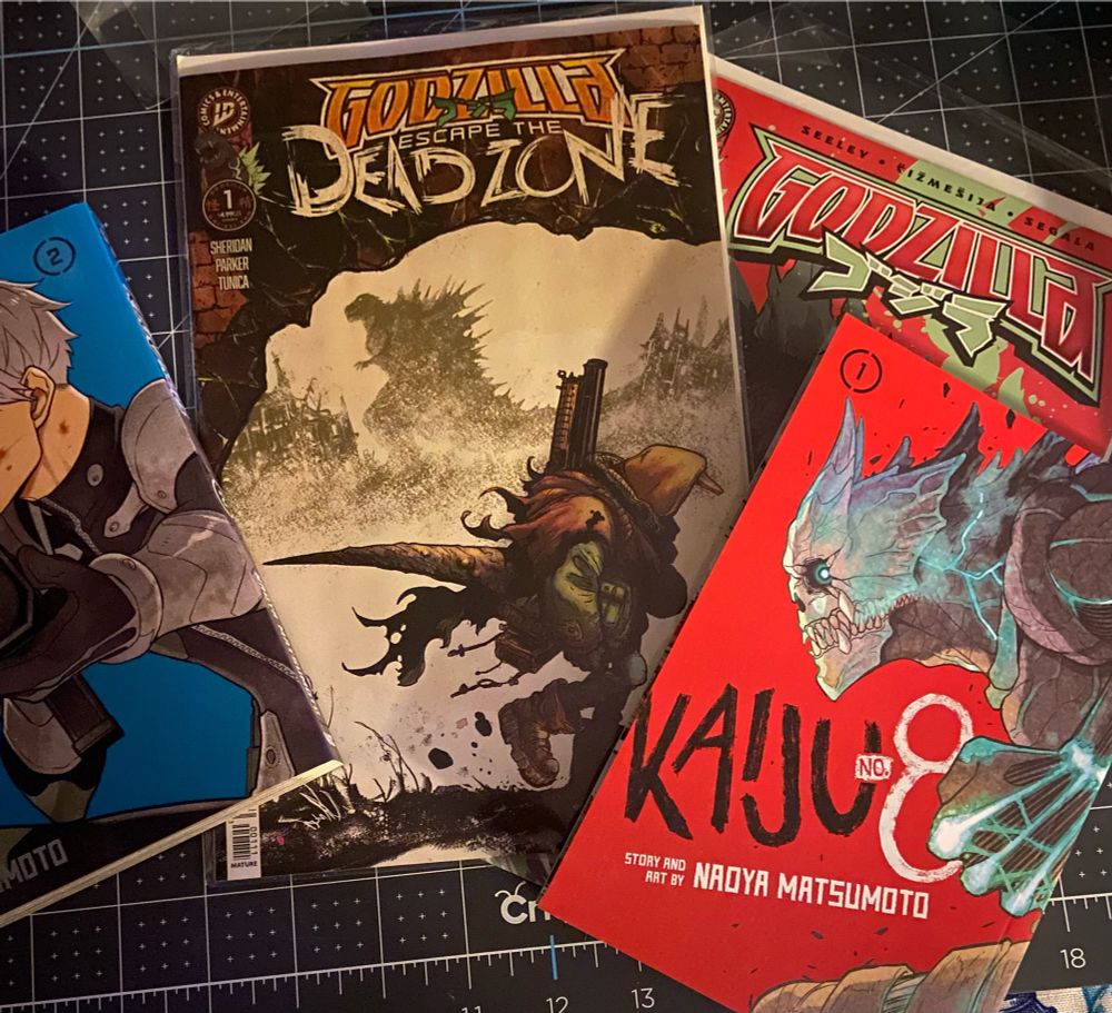 A photo of the covers of Kaiju No. 8 volumes 1 & 2, Issue #1 of Godzilla: Escape the Deadzone, and Issue #1 of Tim Seeley's Godzilla #1.