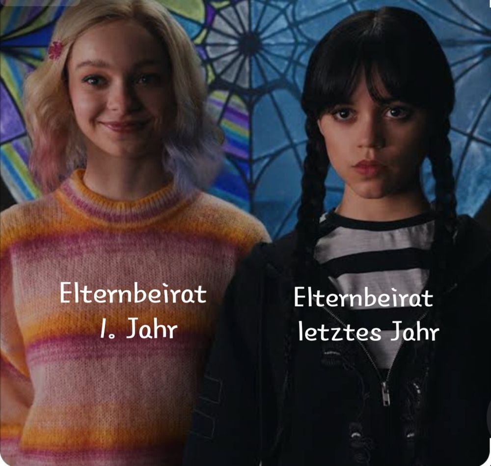 Ein Bild aus der Serie "Wednesday". Links im Bild ist Enid, lächelnd mit offenen blonden Haaren und rosa gefärbten Spitzen. Sie trägt einen bunt gestreiften Pullover in den Farben rosa bis pink die in orange übergehen. Hinter ihr ist ein zweigeteiltes Glasfenster in Form einen Spinnenweben, das auf ihrer Seite bunt ist. Neben ihr (rechte Seite) steht Wednesday Adams. Sie schaut ernst. Ihre schwarzen Haaren sind zu zwei Zöpfen geflochten. Sie trägt ein weiß-schwarz gestreiftes Oberteil und eine schwarze Jacke darüber. Die Seite des Glasfensters besteht aus klarem Glas.

Unter Enid steht "Elternbeirat 1. Jahr" und unter Wednesday steht "Elternbeirat letztes Jahr".