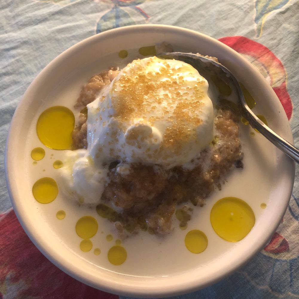 A white bowl of hot cereal on a blue tablecloth printed with peaches. 