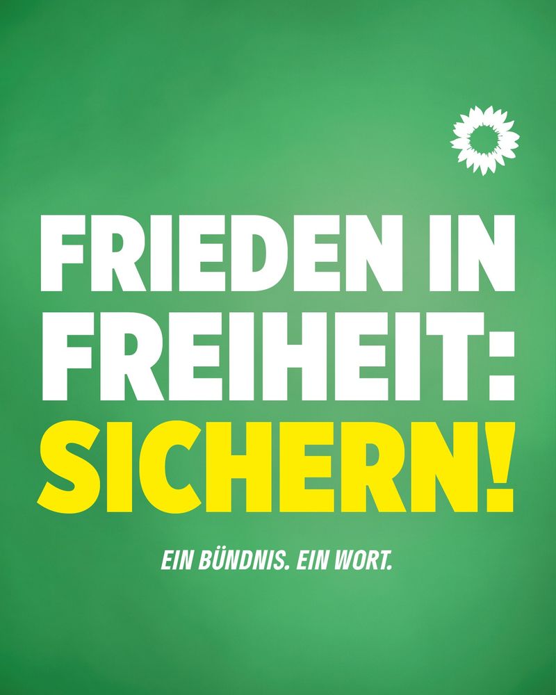 Ein Wahlplakat mit grünem Hintergrund und weißer Sonnenblume. In weißer Schrift die Worte "Frieden in Freiheit: sichern!" "Ein Bündnis". "Ein Wort". 