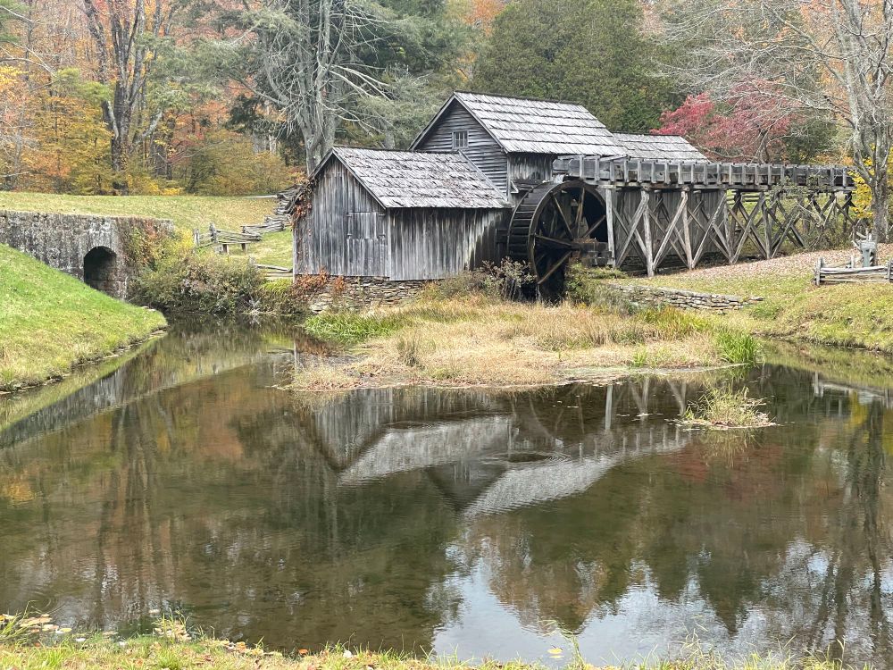 old wooden mill building with a water wheel on a  river in autumn 