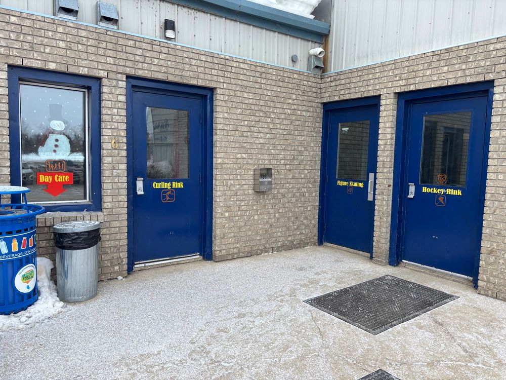 picture of the outside of a brick building with four doors right next to each other, labeled "curling rink," "figure skating," "hockey rink," and "day care"