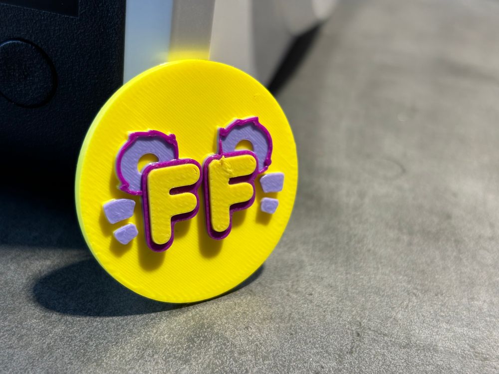 Another 3D-printed coin of the FF logo, this time with lavender, purple, and yellow. 