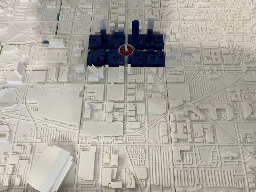 A printed model of downtown Indianapolis with the city flag painted on several blocks around the circle to show how the flag relates to the physical layout of the city.