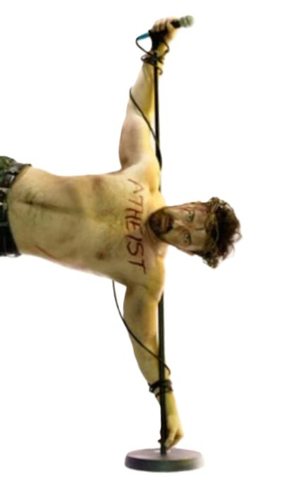 Ricky Gervais, "atheist" written across his chest, has his arms wrapped around an upright microphone stand and is apparently holding his body perpendicular to the ground.