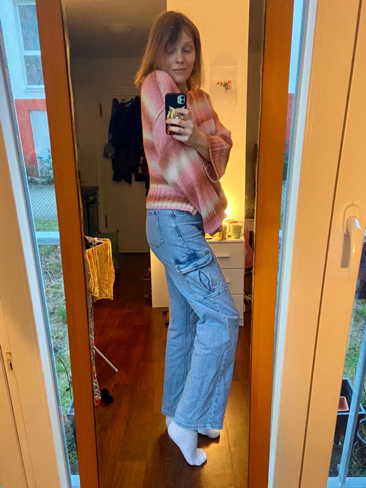 Zoe in a lesbian flag colored sweater