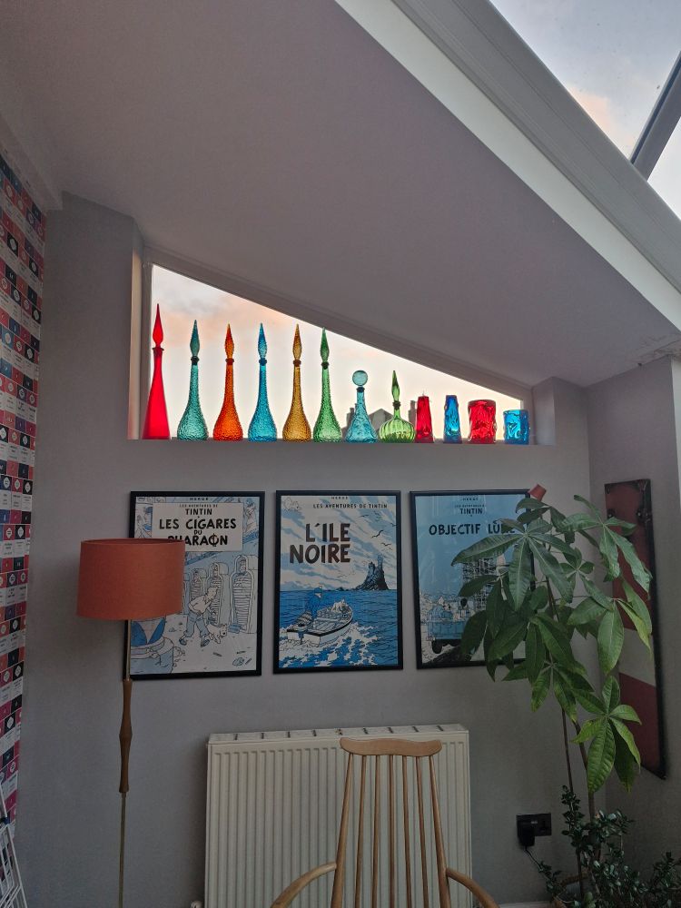 1960s genie bottles on a triangular window with sun rising behind. 