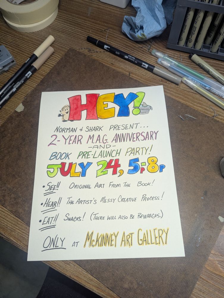 A sign that says "HEY! Norman and Shark present ... 2-year M. A. G. Anniversary and book pre-launch party! July 24th, 5:00 p.m. to 8:00 p.m. See original art from the book! Hear the artist's messy creative process. Eat snacks! (There will also be beverages.) ONLY AT MCKINNEY ART GALLERY! 