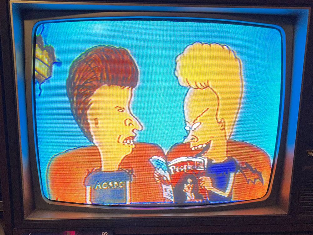 Beavis and Butt-Head sitting on their couch. Beavis is reading People magazine.