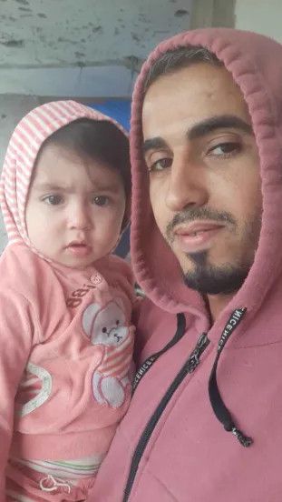 this is the photo i referenced for the previous cartoon. a selfie of Abdulrahman Hajjaj, a 34 year old Palestinian man from Gaza, dressed in a pink hoodie. he is holding his baby daughter, Leen, who wears a pink onesie of a similar color.