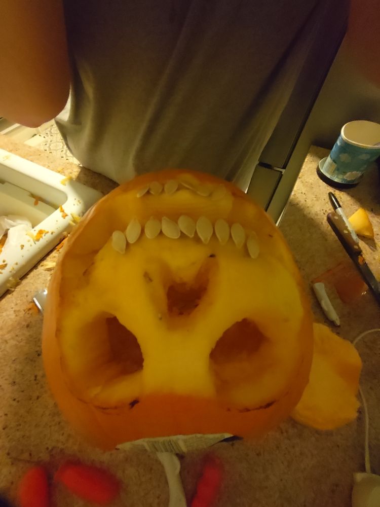 Pumpkin now has been carved I mean skinned and now looks like a skull with teeth also my big lanky ass body is in the way 