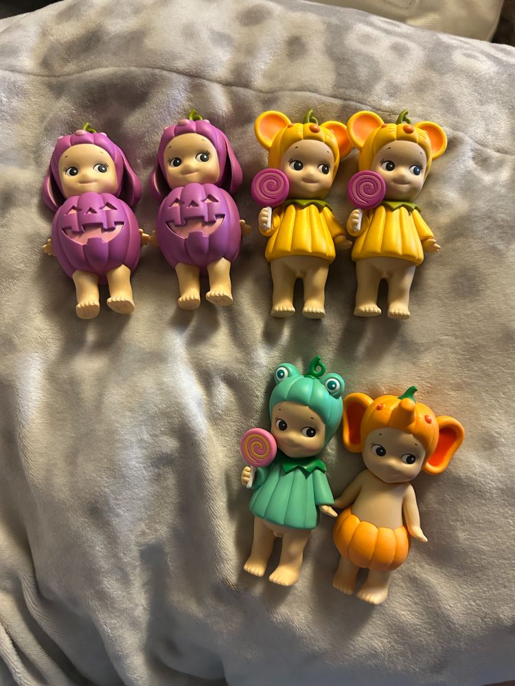 6 Sonny Angels from the Pumpkin Patch series released in 2025. There are 2 purple lop-eared rabbits with jack-o-lantern outfits, 2 yellow mice with pumpkin-textured shirts and a lollipop, a green frog with a pumpkin textured shirt and a lollipop, and an orange elephant with a pumpkin as shorts.