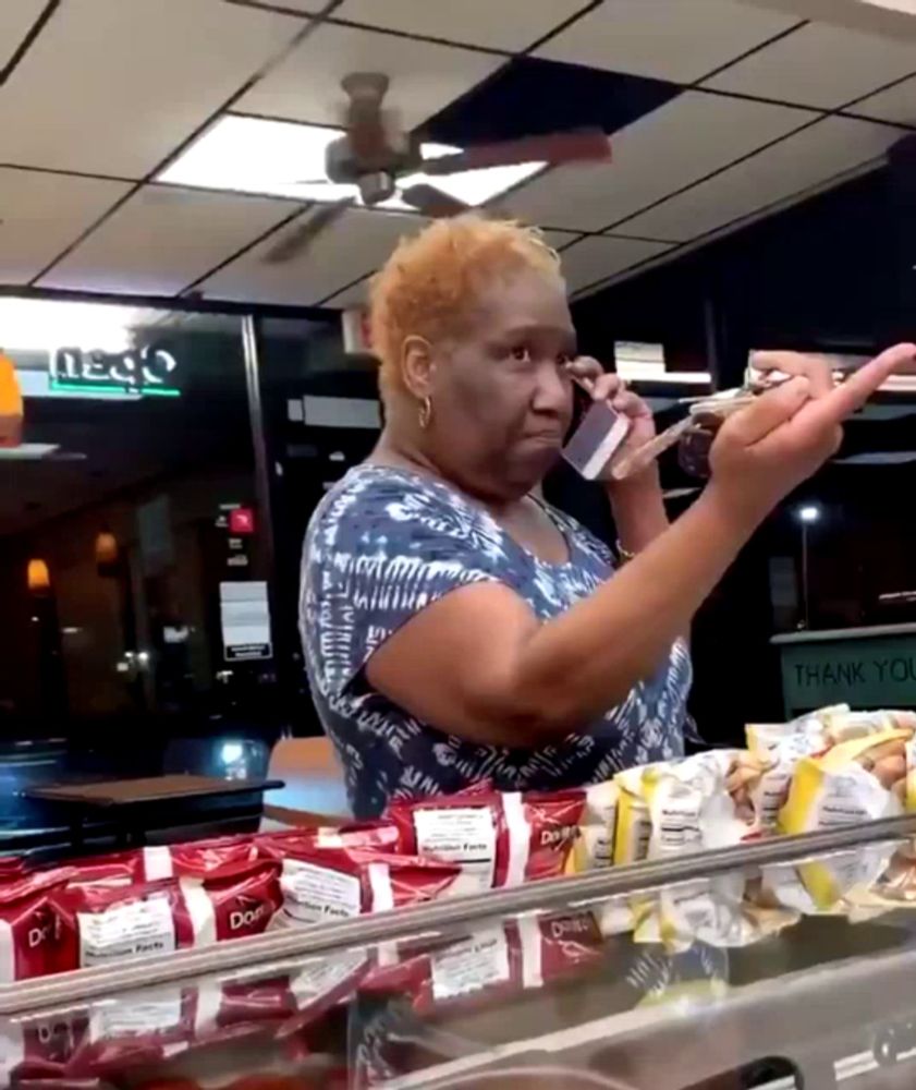 a woman talks on a cell phone in front of a sign that says thank you