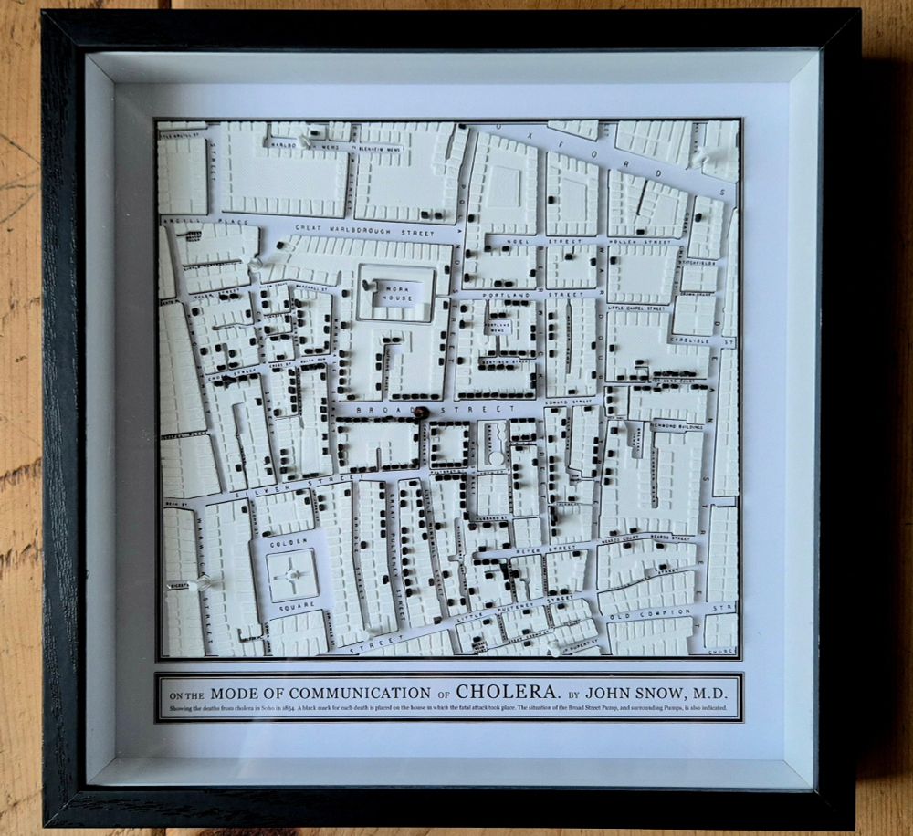 3D-printed map of Soho in 1854. Black marks on top of the buildings represent deaths from cholera caused by infected water from the Broad Street Pump (note the missing handle!). Framed, close-up.