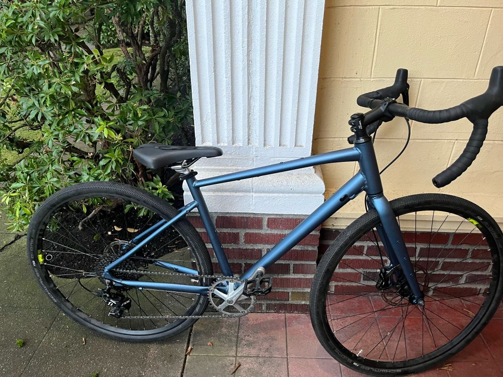 A blue gravel-style road bicycle against the entryway of a brick building