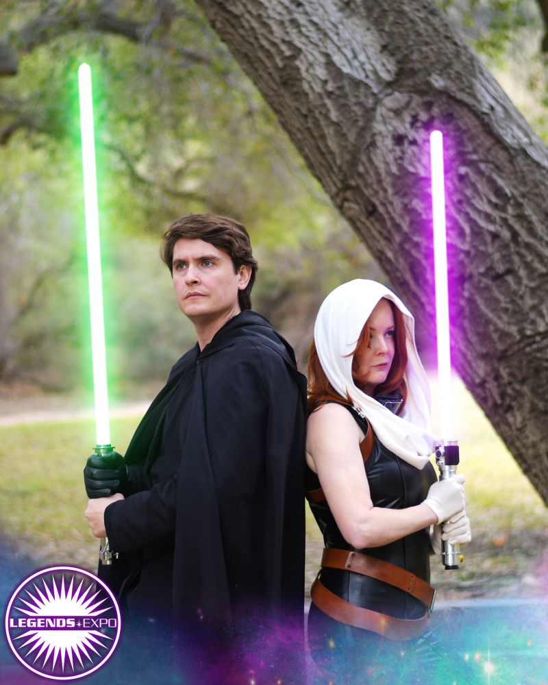 A Luke Skywalker cosplayer (on the left) is back-to-back with a Mara Jade cosplayer (on the right), they are battle-ready and have their lightsabers raised (Luke's is green, Mara's is purple). The lower third of the image is overlayed with a transparent nebula, and the Legends Expo logo.