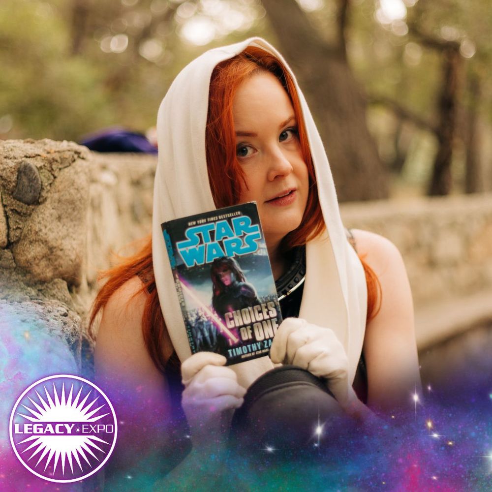 A Mara Jade cosplayer holds up a copy of the novel "Choices of One"