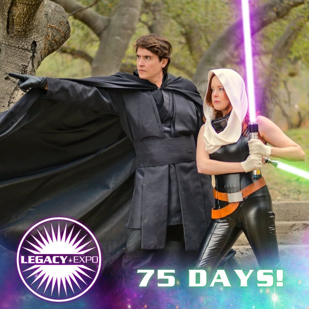 A Mara Jade costumer is holding up their lightsaber; a Luke cosplay stands behind them, pointing on ahead.