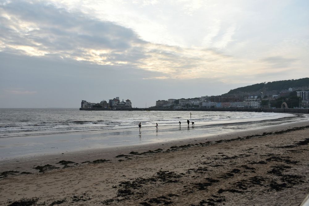 Family paddling at the sea edge on Weston-super-mare beach at dusk