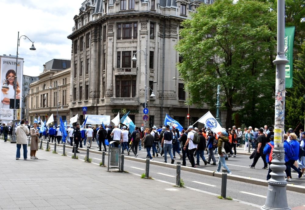 Union March with banners in Bucharest. Bystanders watch as the long column of protesters pass by