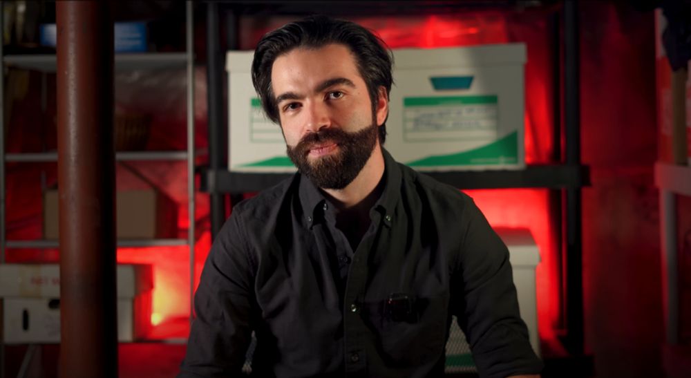 Jacob Geller sitting in front of a number of boxes with red backlighting