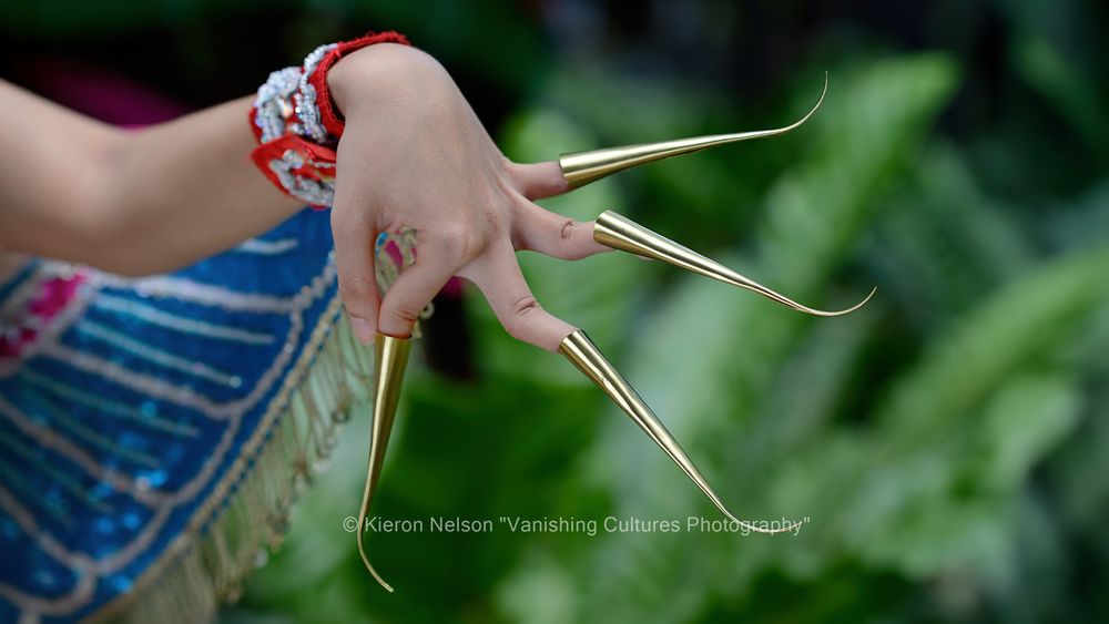 A Thai Dancer is wearing finger stalls of beaten and polished brass; these "fingernails" are about 15 cm (6 ins) long and give a graceful extension to already supple fingers. They are also designed to accentuate the fluid hand movements of Classical Dance. Many of Nora's basic poses are named after various animals, which may indicate their archaic roots in ancient animal movements.