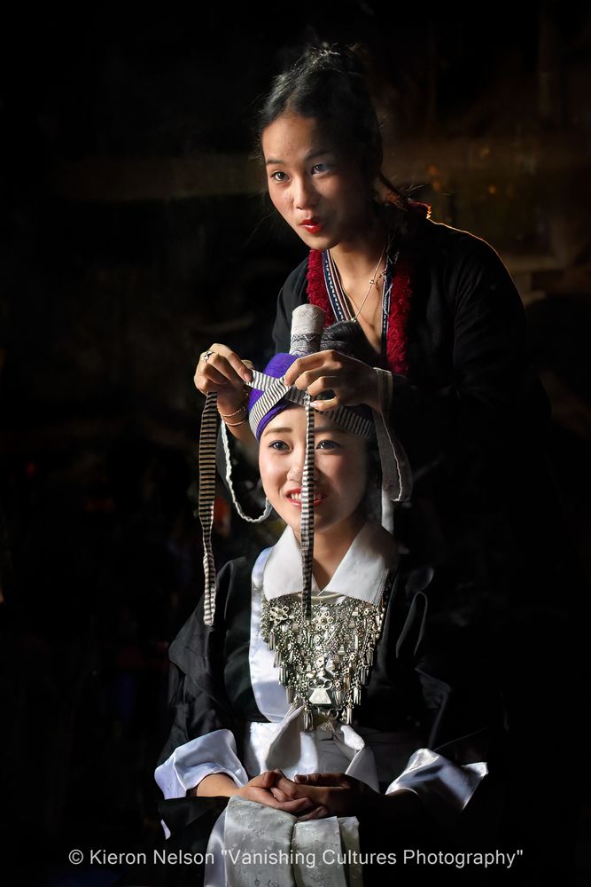 The turban is traditionally created by wrapping a long, dark-colored fabric (often indigo, purple, or black) around the head, with the siv ceeb (black and white striped fabric) placed across the forehead. 